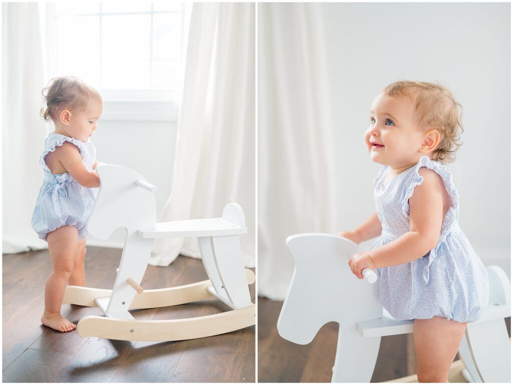 One-year-old baby girl with blue eyes and a lace bow headband, riding a wooden rocking horse during a studio milestone session with Chesapeake baby photographer Jessica Jeremiah.