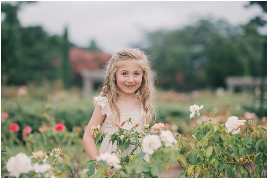 little girl smiling in a rose garden