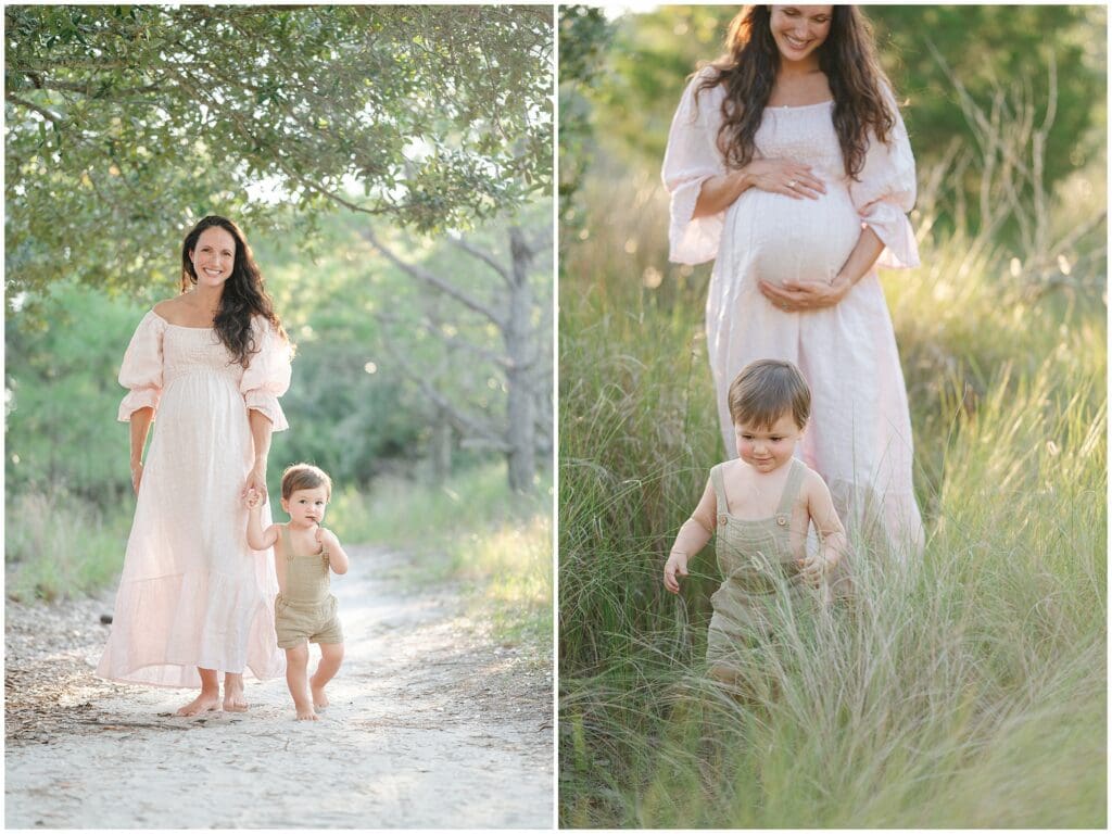 A pregnant mom wearing a pink linen dress walks in a field with her toddler son during a maternity photo session with Jessica Jeremiah Photography in Virginia Beach, VA